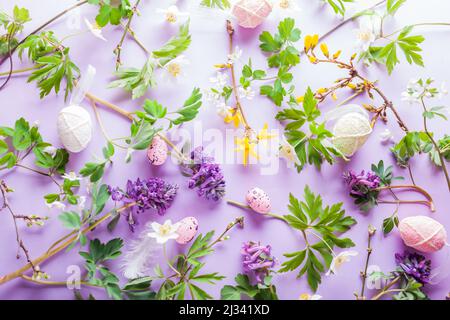 Easter background. Eggs with spring blossoming white yellow flowers on purple background. Holiday texture. Top view Stock Photo