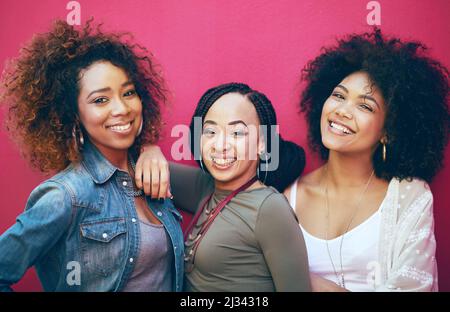 Best friends More like sisters. Portrait of a group of female friends posing against a pink background. Stock Photo