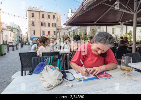 Touorist writing postcards at restaurant table, Gibraltar Stock Photo