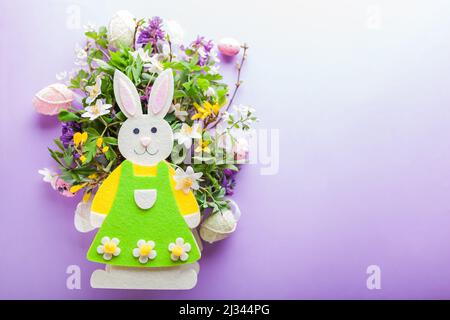 Happy Easter. Easter background with bunny spring blooming flowers and eggs on purple background. Holiday symbol. Space mockup Stock Photo