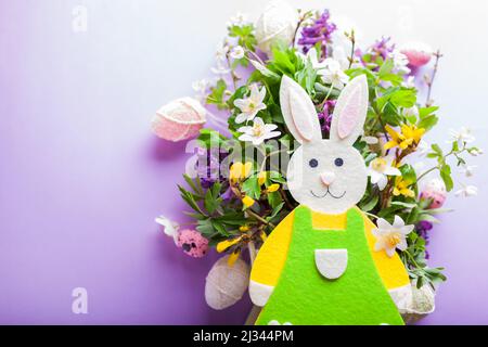 Happy Easter. Easter background with bunny spring yellow white flowers and eggs on purple background. Holiday symbol. Space. Close up Stock Photo