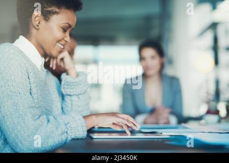 Taking notes on her tablet. Shot of a young businesswoman using her tablet during a meeting. Stock Photo