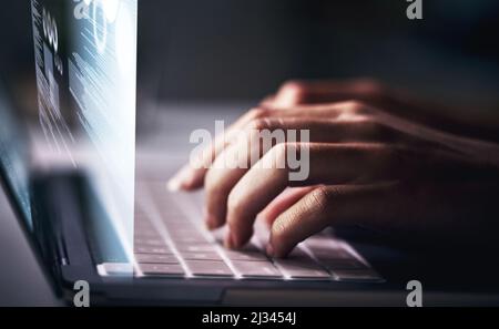 Activating all online systems. Cropped shot of an unrecognizable businesswoman sitting alone in her office at night and using her laptop. Stock Photo