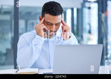 Ive been doing this for too long. Shot of a young businessman experiencing a headache at work. Stock Photo