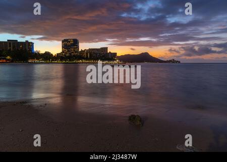 Sunrise over Waikiki beach with an outrigger in the water Stock Photo