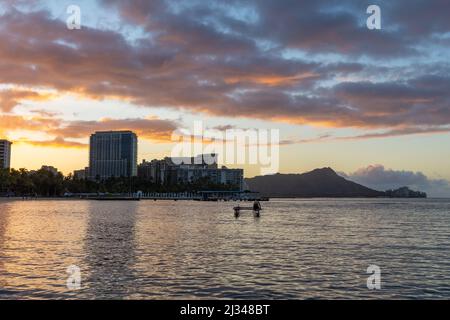 Sunrise over Waikiki beach with an outrigger in the water Stock Photo