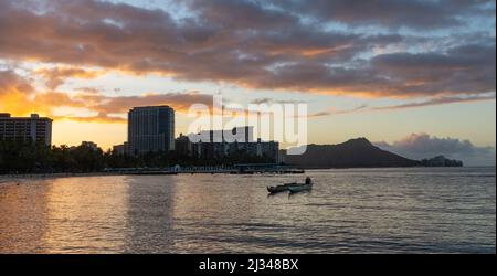 Sunrise over Waikiki beach with an outrigger in the water Stock Photo