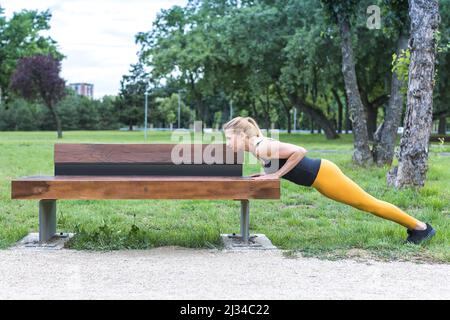 young woman doing standing push-ups outdoors Stock Photo