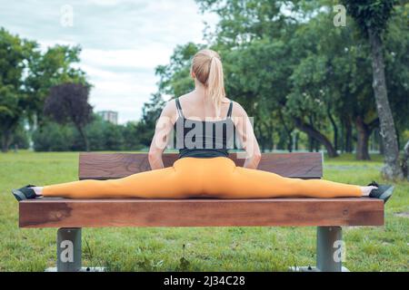 young woman doing split on a park bench Stock Photo