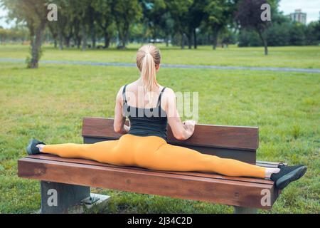 young woman doing split on a park bench Stock Photo