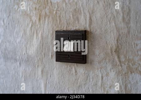 Filthy old square light switch on a wall. Retro toggle switch in an East German apartment. Interior design of the past in a bad condition. Dirt stains Stock Photo
