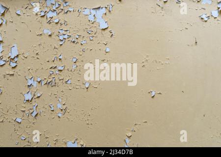 Paint on a beige wall peeling off. Abstract background of a vintage wall inside in an abandoned building. Interior design texture of a ruin. Backdrop Stock Photo