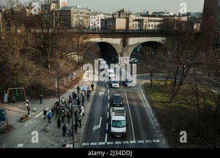 Warsaw. Poland. 03.30.2022. Street traffic. One car after another stopped in front of a pedestrian crossing. People at the bus stop are waiting for th Stock Photo