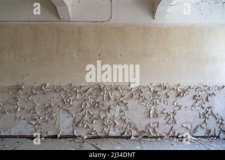 Broken wall with paint peeling off background picture. Abstract backdrop of an abandoned building in bad condition with a lot of dirt and damage. Stock Photo
