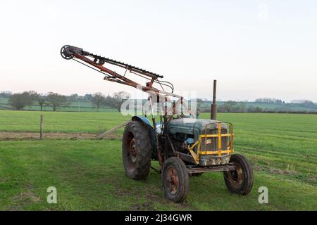 An old antique hedge trimmer mounted on a vintage tractor Stock Photo