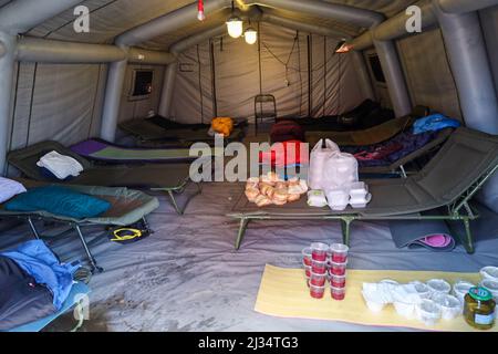 Tesco, Poland. 5th Apr, 2022. Bags of food from World Central Kitchen sit on cots in tent at Tesco, where Firemen sleep who are there to assist the Ukrainian refugee crisis. Tesco in Przemysl is a former grocery-store turned Humanitarian aid Center where many Ukrainian refugees go as soon as they cross over the border into Poland. Dozens of aid organizations are set up and providing shelter, logistical support, SIM cards, internet food and health: everything to quickly care for and relocate refugees, all at no expense to them. Hundreds of volunteers show up from all over the world eager to Stock Photo
