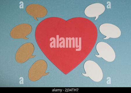 Many speech bubbles surrounding a large red heart against a blue background Stock Photo