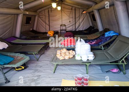 Przemysl, Poland. 5th Apr, 2022. Bags of food from World Central Kitchen sit on cots in tent at Tesco, where Firemen sleep who are there to assist the Ukrainian refugee crisis. Tesco in Przemysl is a former grocery-store turned Humanitarian aid Center where many Ukrainian refugees go as soon as they cross over the border into Poland. Dozens of aid organizations are set up and providing shelter, logistical support, SIM cards, internet food and health: everything to quickly care for and relocate refugees, all at no expense to them. Hundreds of volunteers show up from all over the world eager Stock Photo