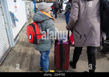 Przemysl, Poland. 4th Apr, 2022. A child and adult Ukrainian Refugees waiting to get on the bus for the train station and then to their new homes in Poland and abroad. Tesco in Przemysl is a former grocery-store turned Humanitarian aid Center where many Ukrainian refugees go as soon as they cross over the border into Poland. Dozens of aid organizations are set up and providing shelter, logistical support, SIM cards, internet food and health: everything to quickly care for and relocate refugees, all at no expense to them. Hundreds of volunteers show up from all over the world eager to assist Stock Photo