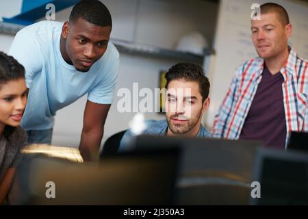Design is what we do. Shot of team of colleagues using a computer together in a modern office. Stock Photo