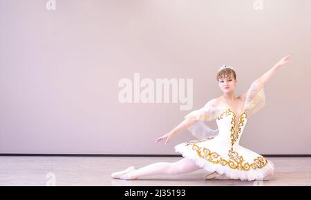 young caucasian ballet dancer practice ballet positions in professional tutu skirt of white swan Stock Photo