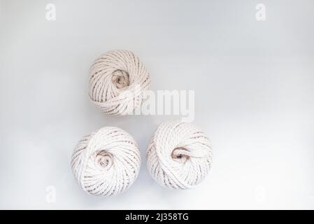 bobbins of light beige pastel color together for weaving macrame needlework on a light background Stock Photo