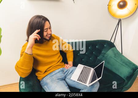 Smiley caucasian freelance businessman sitting on a sofa with laptop on his leg. Modern online life concept. High quality photo Stock Photo