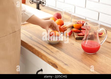 Woman making fresh orange juice on wooden table Stock Photo