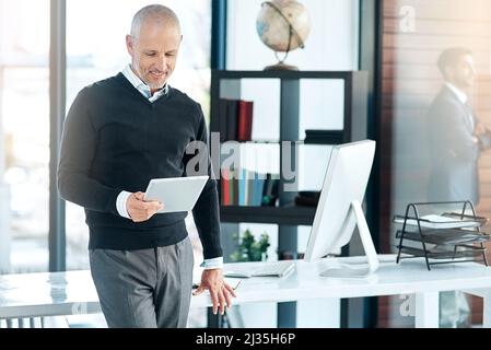 I pay attention to customer feedback to better my company. Shot of a mature businessman using his digital tablet at the office. Stock Photo