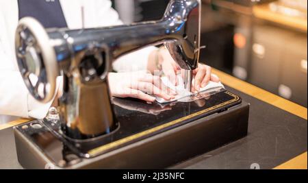 Female hand using vintage sewing machine scribbling fabric and repairing the cloth at home. Stock Photo