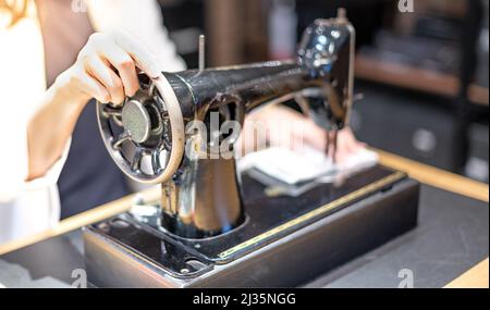 Female hand using vintage sewing machine scribbling fabric and repairing the cloth at home. Stock Photo