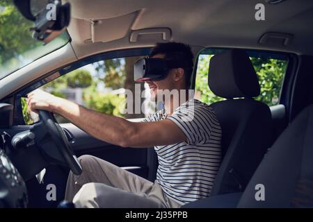 Lets take this new technology for a test drive. Shot of a happy young man driving a car while wearing a virtual reality headset. Stock Photo