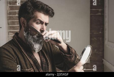 Barbershop concept. Hairdresser makes hairstyle a man with a beard. Bearded client visiting barber shop. Beard care. Senior man visiting hairstylist Stock Photo