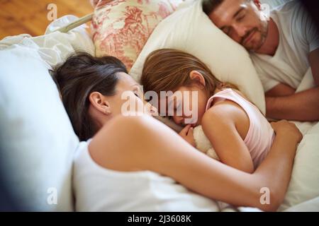 Family snuggle time. Shot of a family sleeping in bed at home. Stock Photo