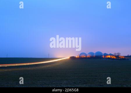 06 April 2022, Saxony-Anhalt, Hohe Börde: A gloomy day dawns over a biogas plant. Next to it, the first commuters drive along a country road. It is supposed to remain cloudy and rainy in the region. It is also supposed to become stormier again. A change in the weather is not in sight. Photo: Klaus-Dietmar Gabbert/dpa/ZB Stock Photo