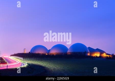 06 April 2022, Saxony-Anhalt, Hohe Börde: A gloomy day dawns over a biogas plant. Next to it, the first commuters drive along a country road. It is supposed to remain cloudy and rainy in the region. It is also supposed to become stormier again. A change in the weather is not in sight. Photo: Klaus-Dietmar Gabbert/dpa/ZB Stock Photo