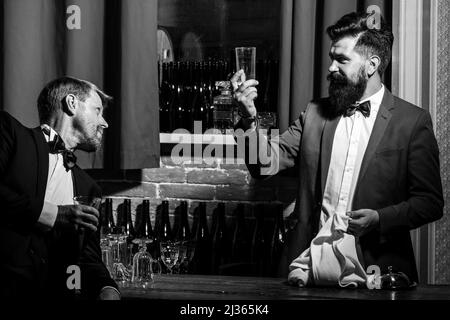 Barmen and customer. Alcohol beverage. Barman at counter. Hipster in bar. Old traditional whiskey drink. Gentlemans beverage. Stock Photo