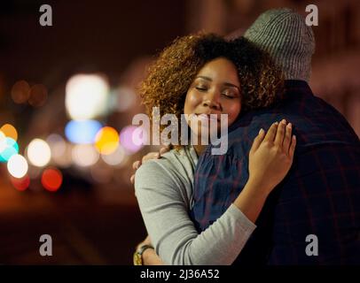 I feel so safe in his arms. Cropped shot of a young couple out on a date in the city. Stock Photo