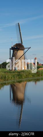 KINDERDIJK, NETHERLANDS - JULY 04, 2019:  Upright panorama of the historic windmills at Kinderdijk with reflection in a canal Stock Photo