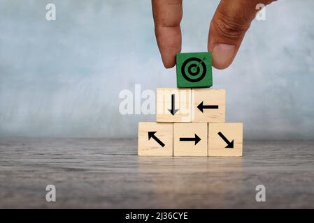 Wooden cubes with target icon and arrow pointing different direction. Organize a team, set a goal. Stock Photo