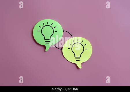 Lightbulb icon on speech bubble and exchange arrow on pink background. Exchange ideas, brainstorming Stock Photo