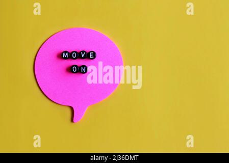 Top view image of alphabet cubes with text MOVE ON on speech bubble. Yellow background. Copy space. Stock Photo