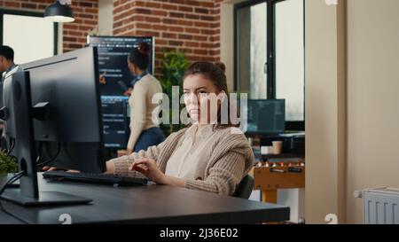 Software engineers analyzing code on wall screen tv looking for bugs and errors while colleague programer typing sitting at desk. App developers working on online cloud computing group project. Stock Photo