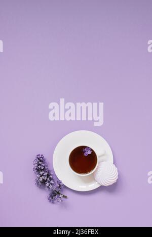 Flower arrangements of beautiful purple lilac on a purple background with a cup of tea. Women's office desk, stylish stock image, Flat layout, top vie Stock Photo
