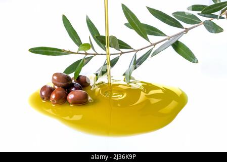 Pouring olive oil with olives and branch with olive leaves isolated on white Stock Photo