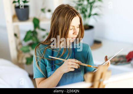 Fine art school. Closeup of artist portrait ,hands holding wooden palette, mixing acrylic paint with brush.Artist woman with paint palette.Hand with brush painting.  Stock Photo