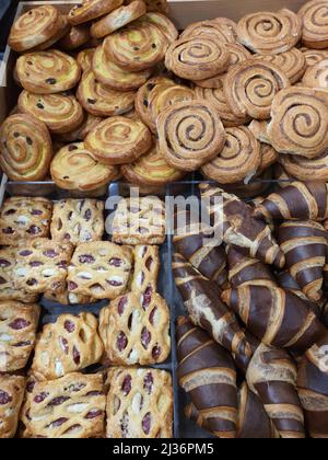 Freshly baked sweet frozen puff shortcrust pastry with jam and cream cheese in bakery. Chocolate croissants, pudding and cinnamon rolls in grocery store. Fresh dessert or afternoon snack Stock Photo