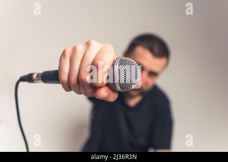 good-looking European young bearded man with mustache tattoos and microphone looking into the camera medium closeup studio shot light background. High quality photo Stock Photo