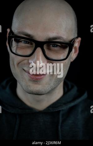 Portrait of a bald young man with eyeglasses smiling Stock Photo