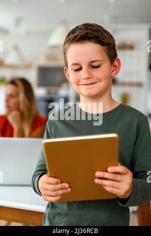 Home schooling social distance e-learning online education concept. Happy boy using tablet at home. Stock Photo